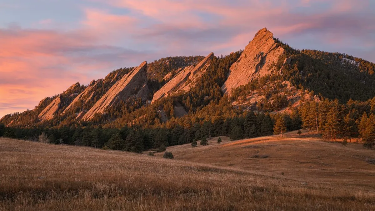 The Flatirons above Boulder glowing orange at sunrise