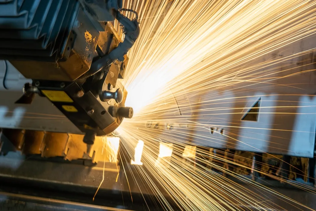 Sparks spraying from a machine as it cuts a sheet of metal
